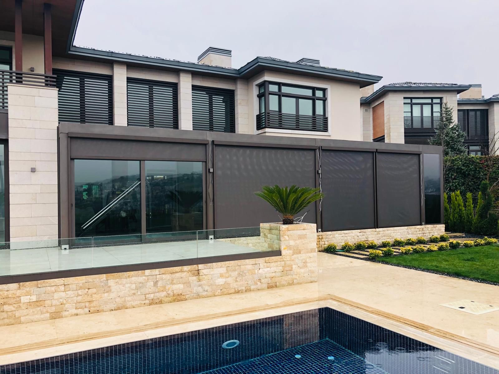Dark gray privacy fence on light stone base with greenery