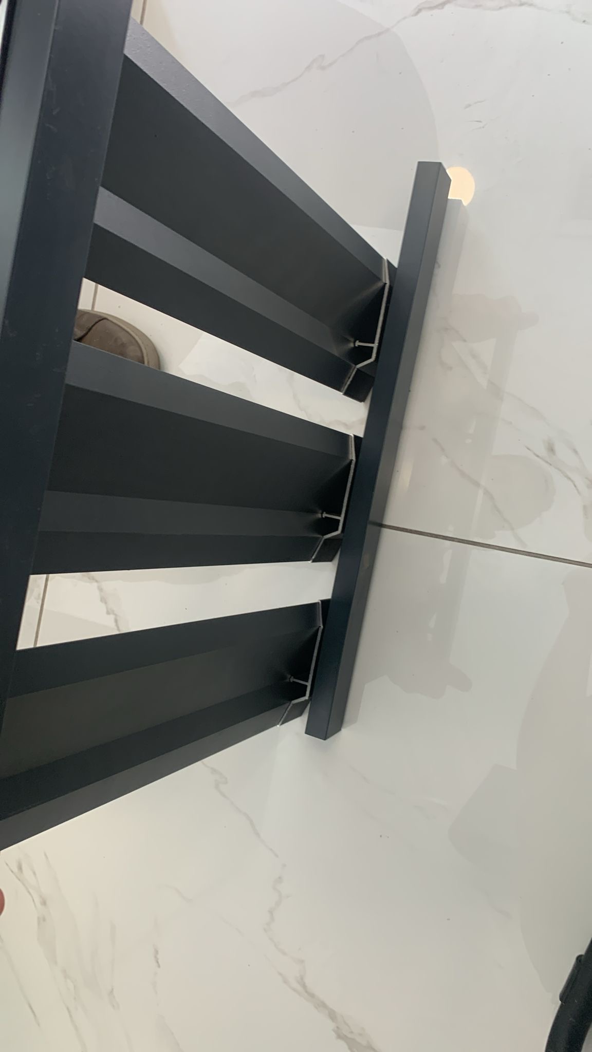 Louvered fence extending along concrete base under blue sky