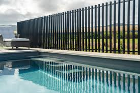 Black slat fence by pool with green landscape